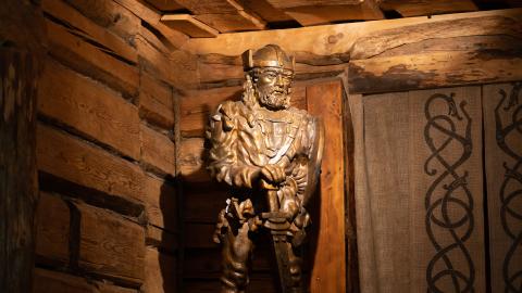 Bronze statue of a Viking in the corner of a log cabin