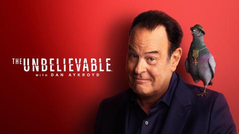 Dan Aykroyd next to the show title with a one-legged pigeon standing on his shoulder. The pigeon is wearing a WWI helmet and has a military medal around its neck