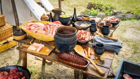 Chopped raw meat, homemade food and pottery on the table at historical reenactment of Vikings lifestyle around 11th century