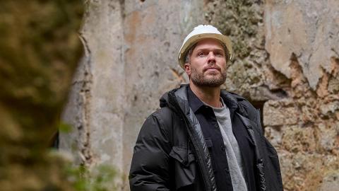 Rick Edwards wearing a hard hat in the ruins of a castle