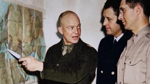 General Dwight Eisenhower points to a map during Operation Torch planning in World War II as military staff look on.
