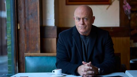 Ross Kemp sitting in a cafe with a small coffee cup 