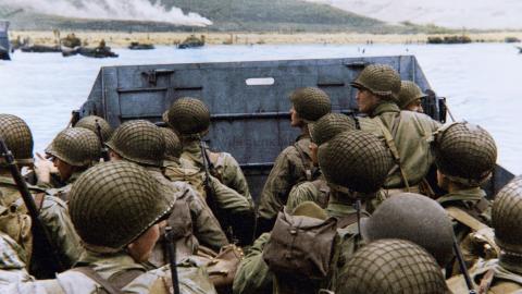 Soldiers aboard a landing craft approach the Normandy beaches during D-Day, depicted in a World War II documentary or drama.