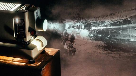 Photo of a projector and a World War Two image of a flugzeugträger bombing