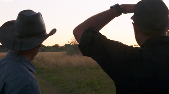Silhouette of two men looking towards the horizon