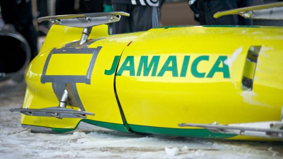 A yellow bobsled with Jamaica written on it in green letters