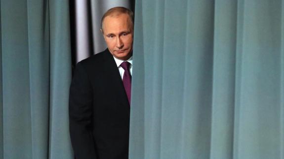 Vladimir Putin standing behind a teal green curtain