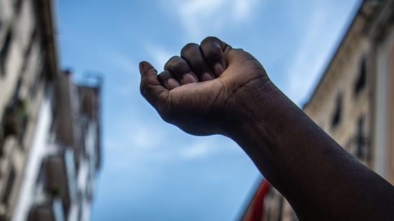 The raised fist. A black man raises his fist to the sky during a migrants protest against racial discrimation. Black power, revolution. Black Lives Matter