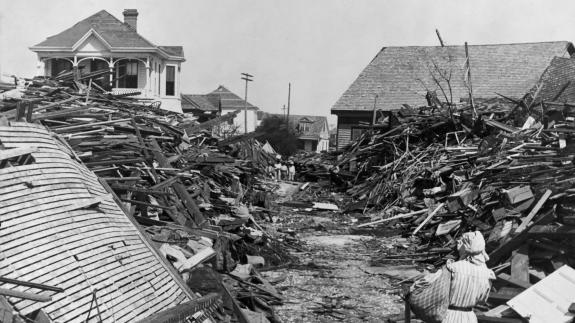 Woman walks through a passageway amongst houses flattened by the hurricane.