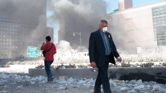 Two civilians walk the streets of New York with smoke billowing behind them