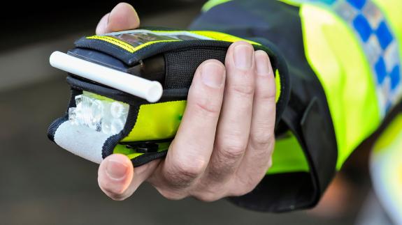 A police officer holds a roadside breathalyser alcohol breath test after taking a sample from a driver.