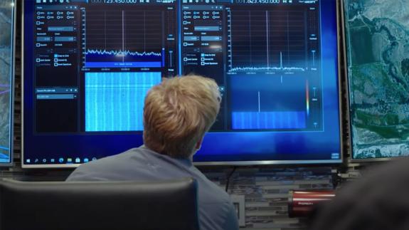 Dr Travis Taylor looking at charts and graphs on a large computer screen