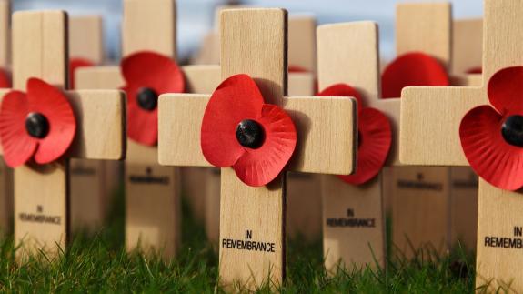 Poppies on small wooden crosses that say 'In Remembrance'