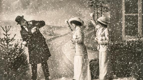 A vintage picture of two women and a man throwing snowballs