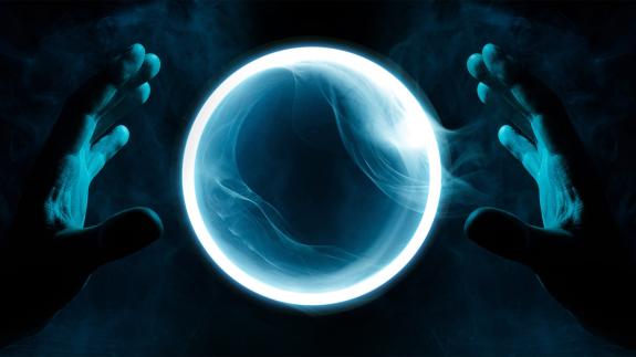 Two hands hover over a luminescent crystal ball