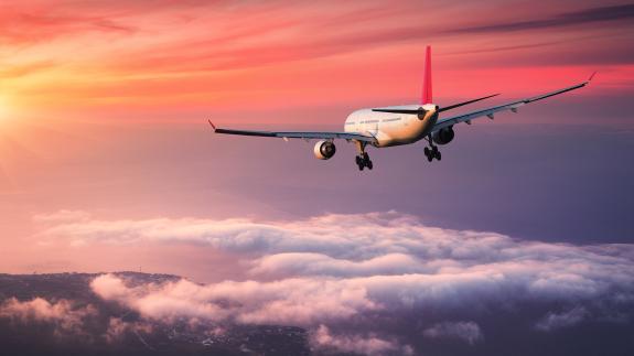A photograph of a aeroplane flying into the sunset