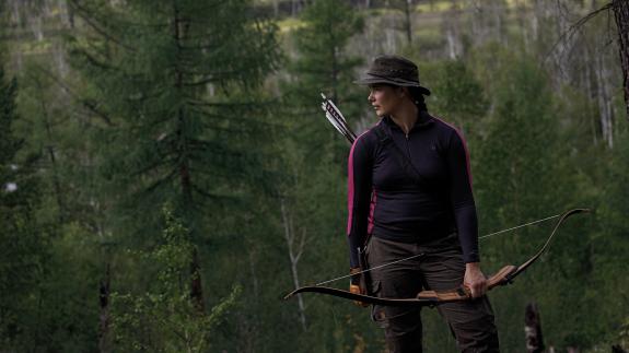 Carleigh Fairchild holding a bow and arrow in the forest