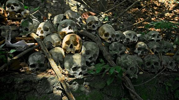 A pile of human skulls lie on the forest floor in an abandoned cemetery 