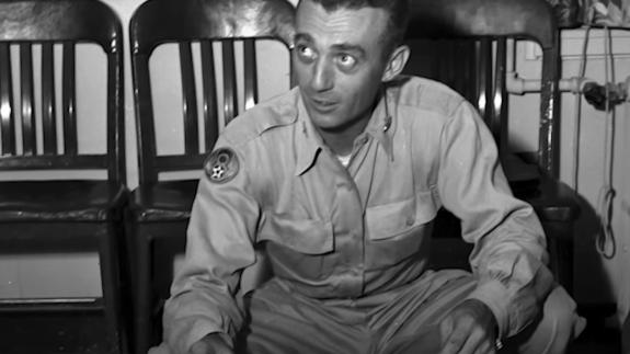 Black and white photograph of a soldier looking at potential evidence of a UFO