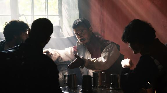 An actor portraying Robert Catesby talks to acquaintances 