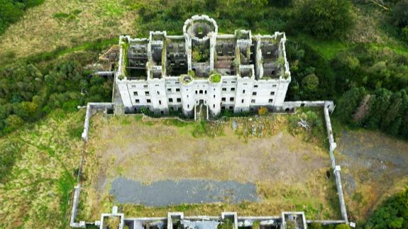 An aerial shot of an abandoned castle in the Scottish countryside