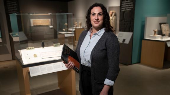 Dr Meredith Brand holding a book inside a museum