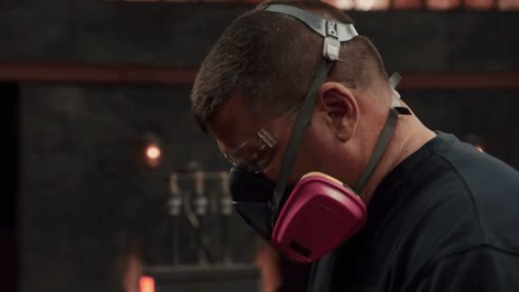 Forged in Fire bladesmith wearing protective glasses and mask while using equipment