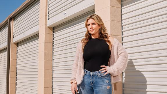 Brandi Passante stands with a hand on her hip in front of some storage lockers