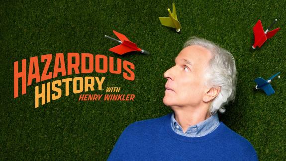 Henry Winkler looks up nervously as giant lawn darts land around him beside the title 'Hazardous History'
