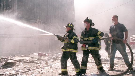 Firefighters spray a hose in the aftermath of the 9/11 attacks