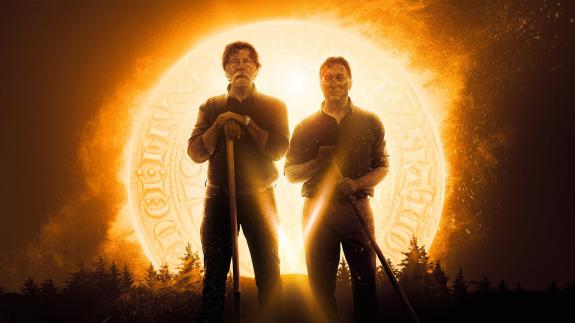 Rick and Marty Lagina hold shovels while standing in front of a glowing golden coin