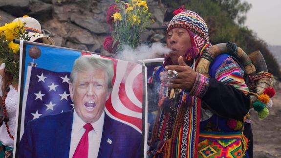A Preuvian shaman blows smoke on an image of Donald Trump
