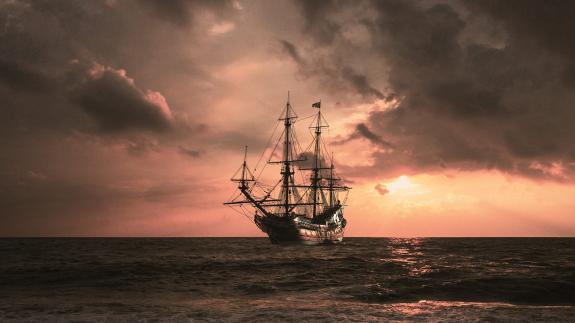 A pirate ship on the sea at sunset