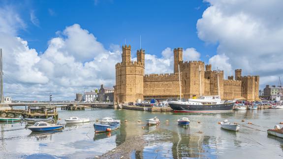 Caernarfon Castle with boats moored on the River Seiont in the foreground