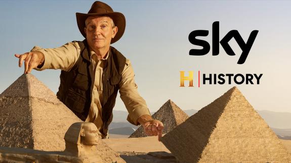 Bradley Walsh looms over the Great Pyramids and lifts one up with his finger - next to the Sky HISTORY logo