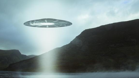 A UFO hovering over a mountain lake with a light beam coming down