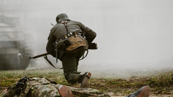 A soldier taking part in a historical reenactment of a WWII fight