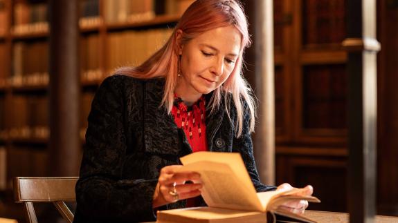 Alice Roberts reading an old book in a library