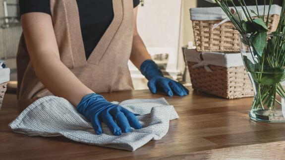 Stock image of someone wiping a surface while cleaning their house