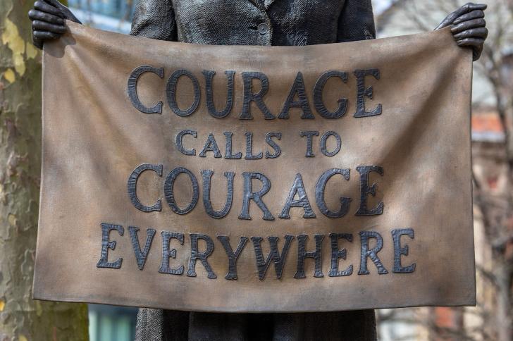 Statue of a suffragette holding a banner saying 'COURAGE CALLS TO COURAGE EVERYWHERE'