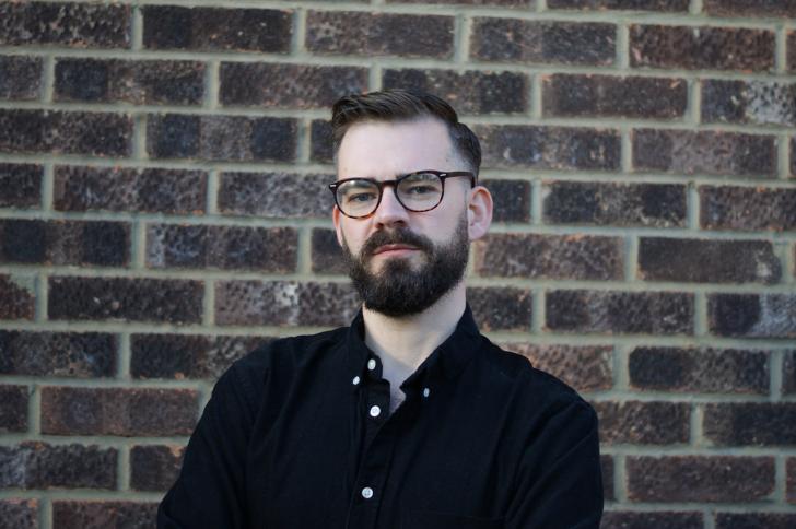 Dr Daniel Cowling standing in front of a brick wall