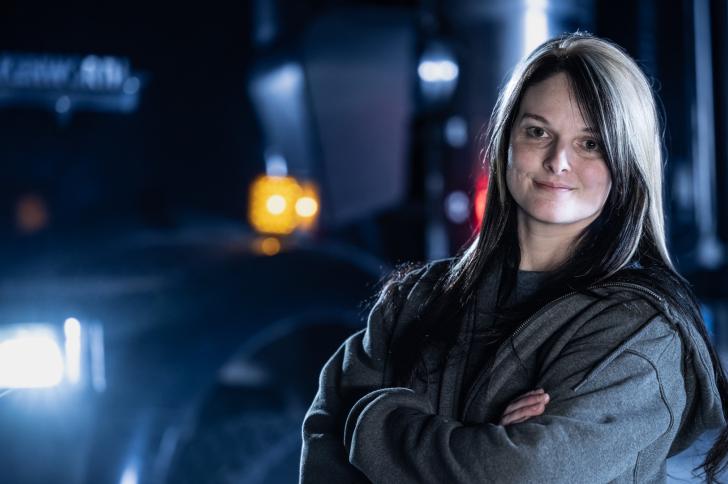 Lisa Kelly standing with her arms crossed in front of a truck