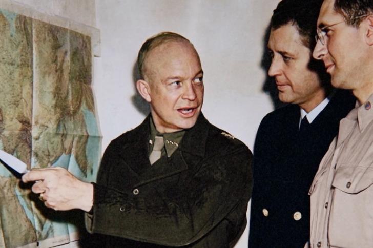 General Dwight Eisenhower points to a map during Operation Torch planning in World War II as military staff look on.