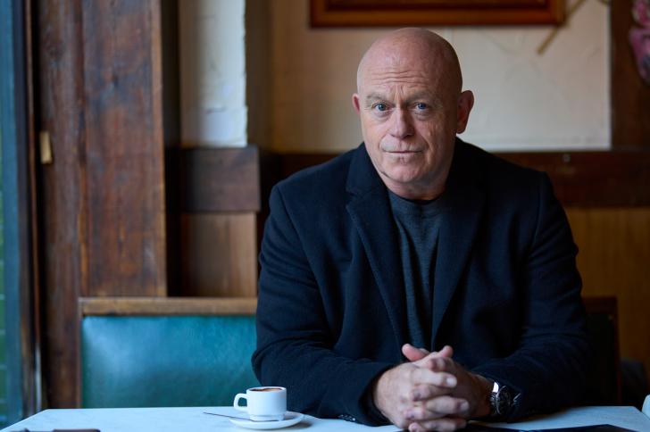 Ross Kemp sitting in a cafe with a small coffee cup 