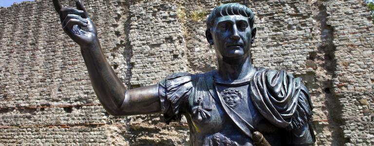 A statue of Roman Emperor Trajan in front of the remains of London Wall