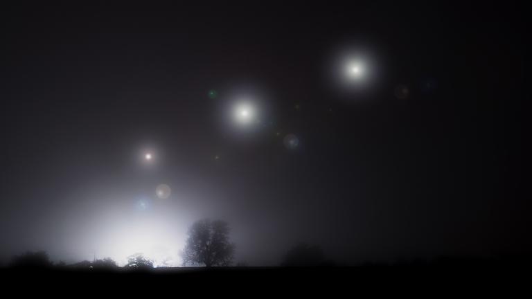 Glowing mysterious lights floating in the sky on a spooky foggy winters night