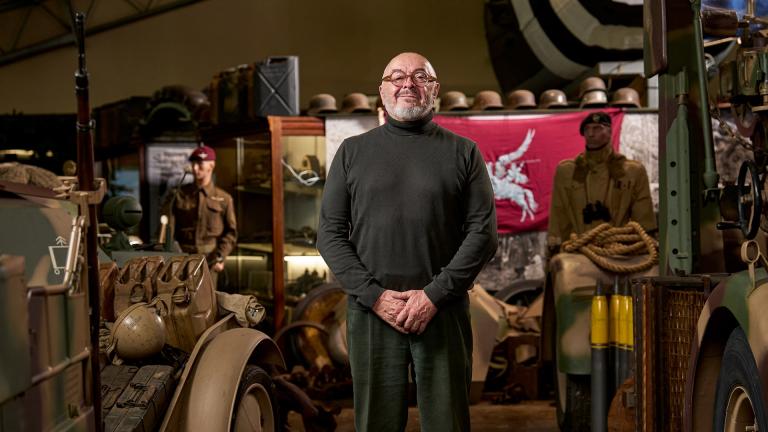 Bruce Crompton standing in front of a lot of military artefacts