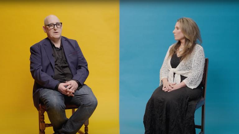 A man and a woman sitting either side of a divided background which is yellow on the left and blue on the right