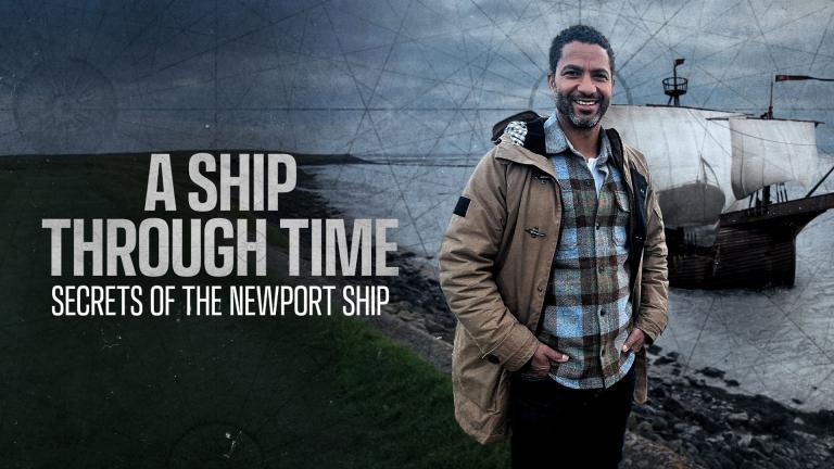 Sean Fletcher stands in front of the River Usk with a rendering of the Newport Ship sailing on it