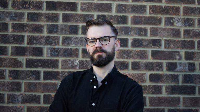 Dr Daniel Cowling standing in front of a brick wall
